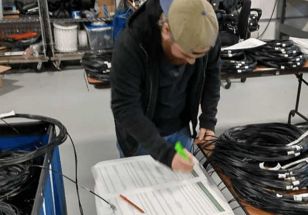 A man is writing on paper in an assembly shop.